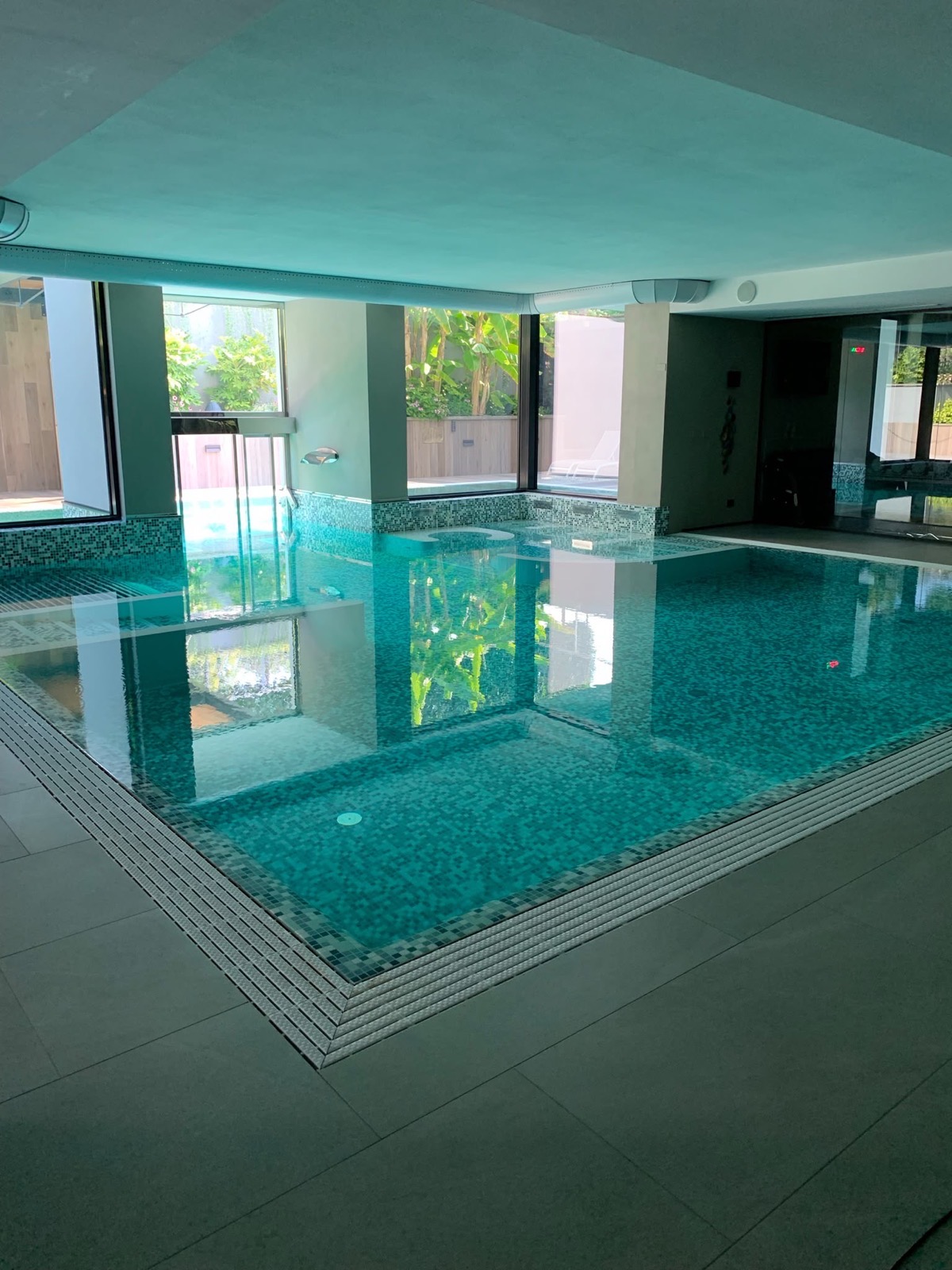 Piscina interna rivestita in mosaico, con il pavimento perimetrale in gres trattato